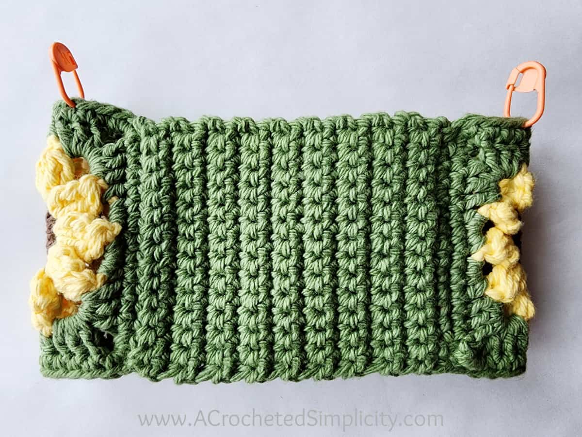 Backside of the sunflower motif loop with stitch markers showing where to begin the crochet hand towel.