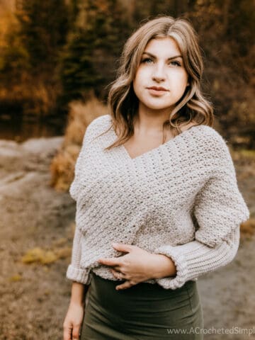 Woman modeling a crochet scarf with sleeves as a wrap for the featured image