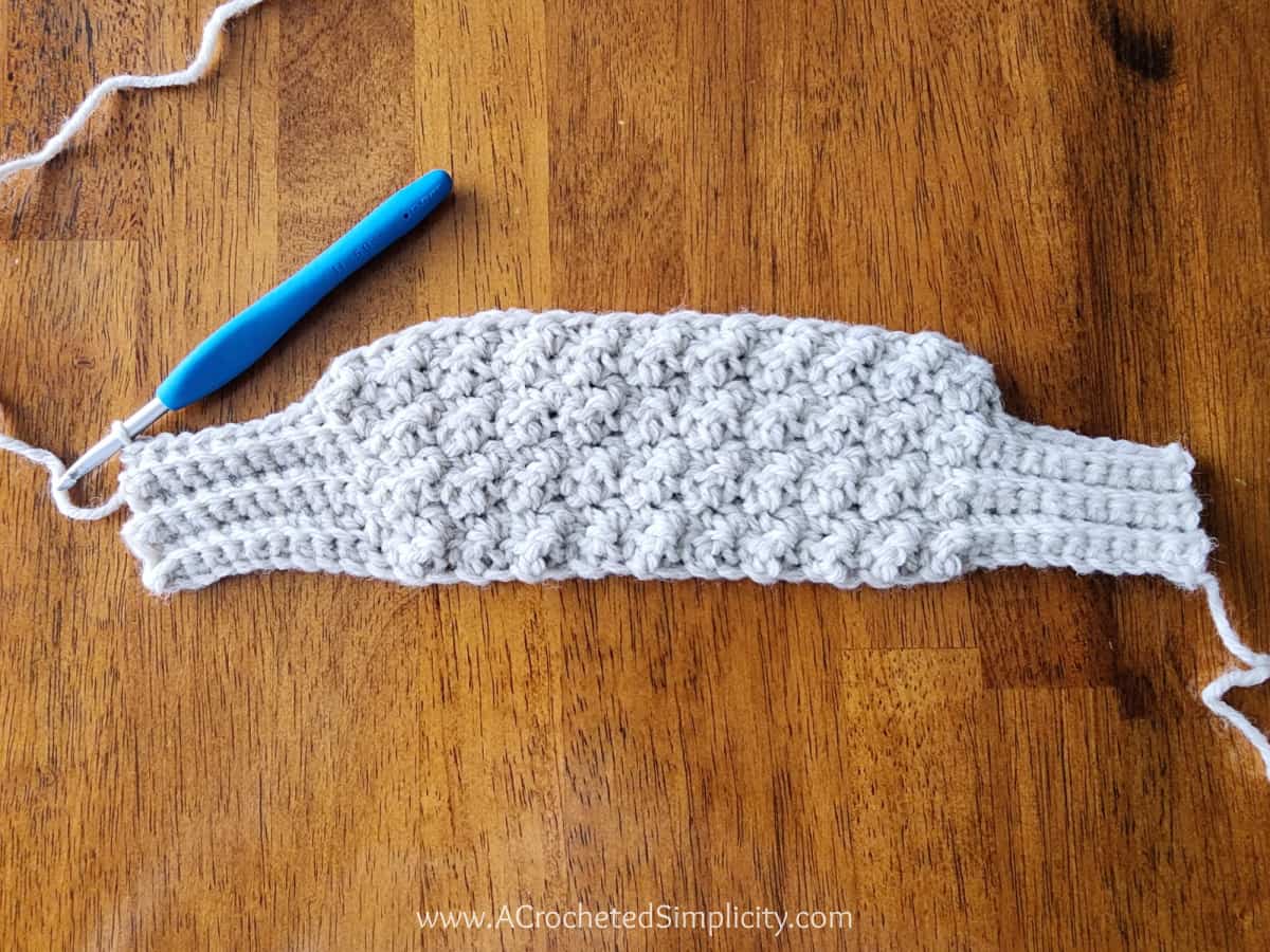 Crochet sweater scarf tutorial showing how to go from the shorter rows to the longer row.