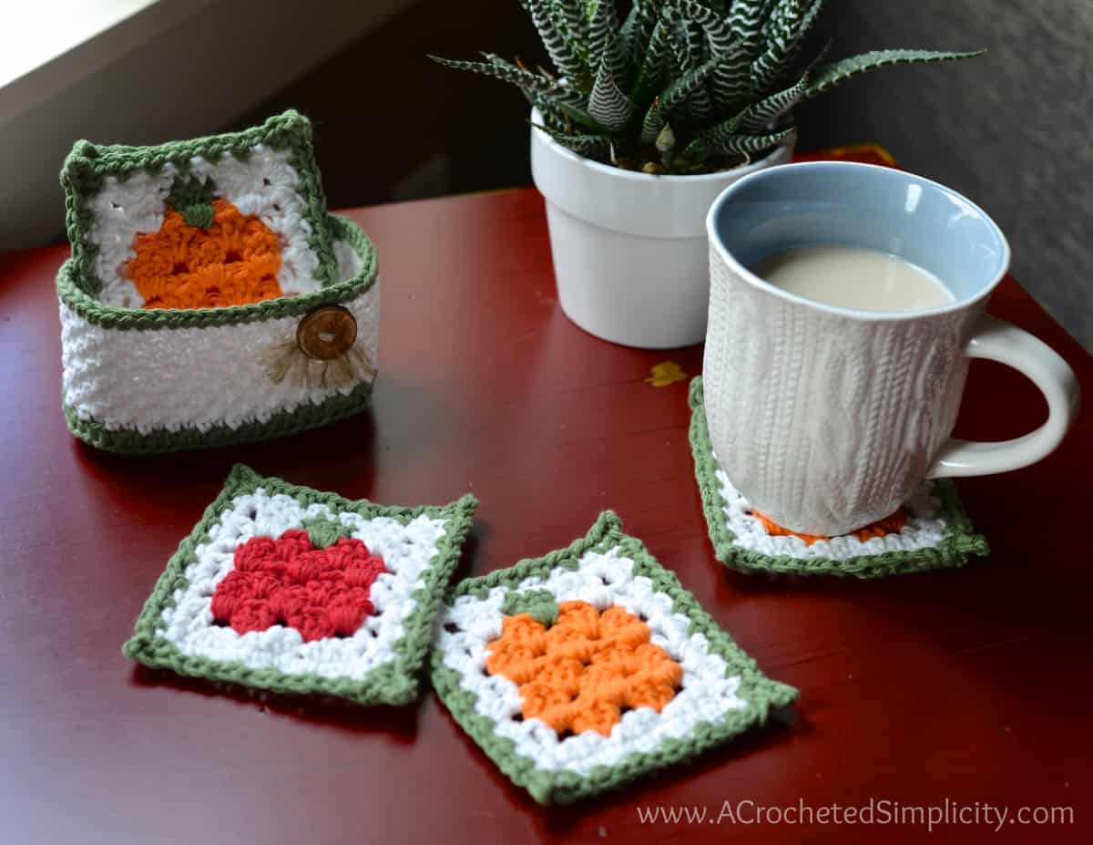 Fall crochet coaster set with holder sitting on red table with coffee mug