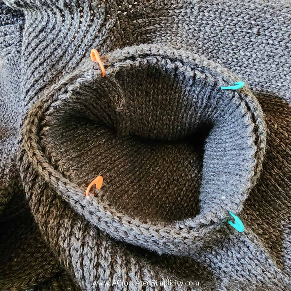 Photo shows the use of locking stitch markers to hold the sleeve to the armhole opening during seaming.