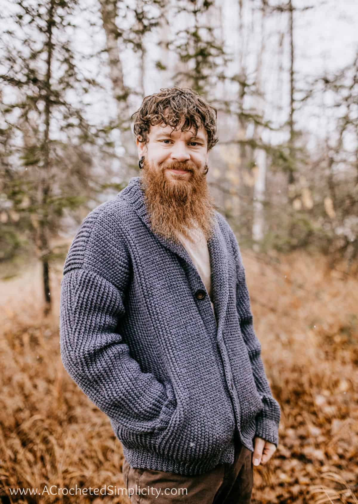 Man modeling a shawl collar cardigan standing in the woods during the fall