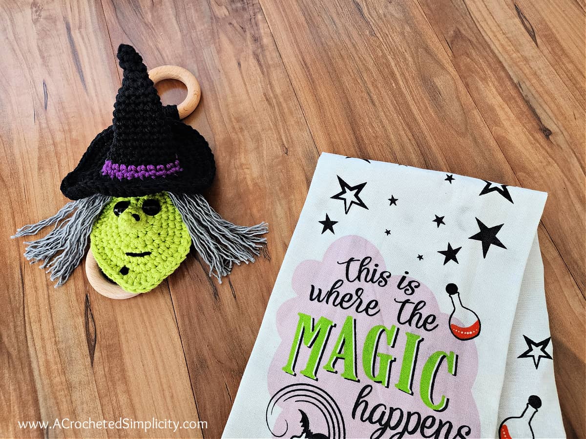 Witch crochet towel ring holder with ring laying on wood floor.