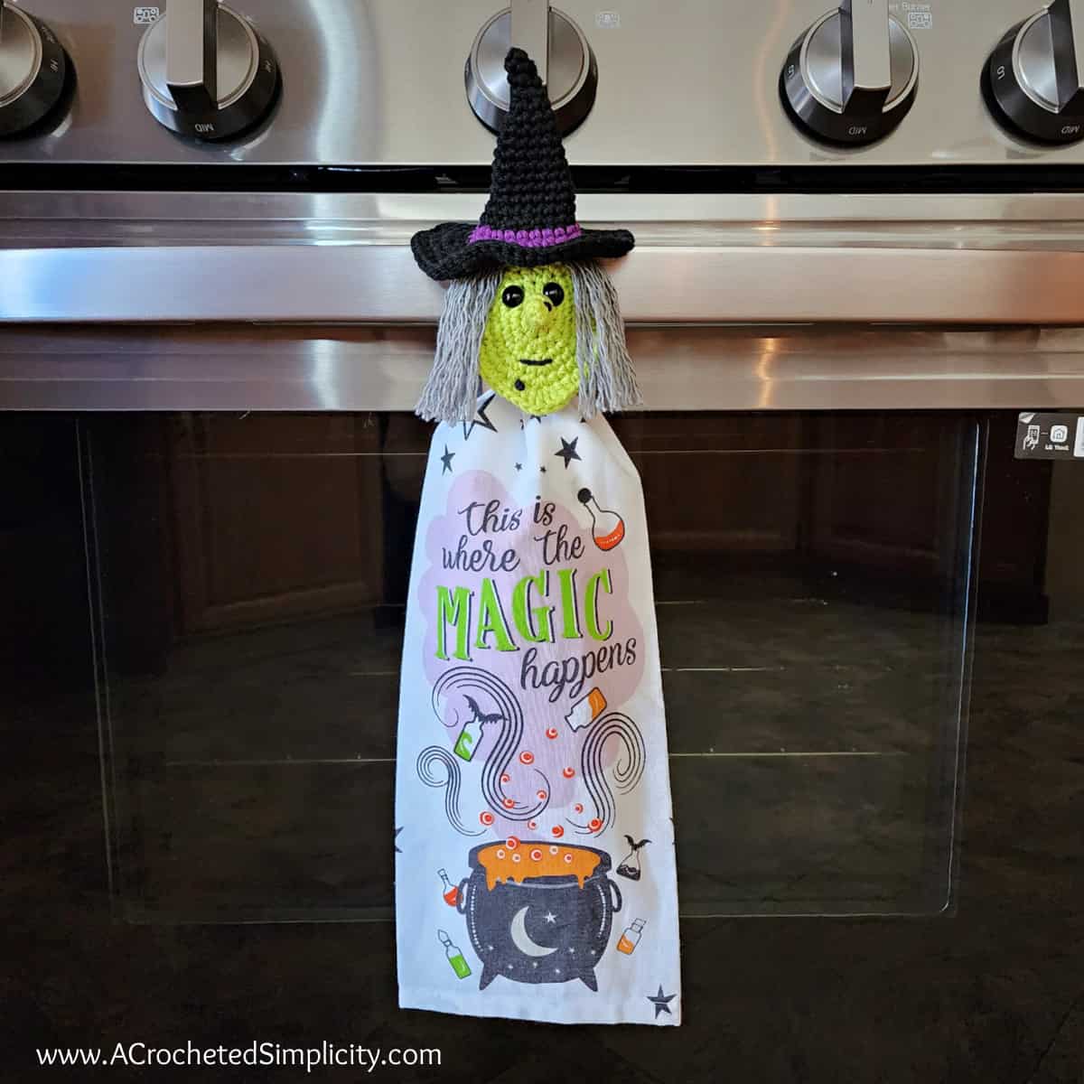 Halloween witch crochet towel holder on stove holding kitchen towel.