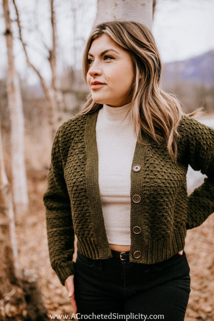 Woman wearing olive green granny stitch button up crochet cardigan