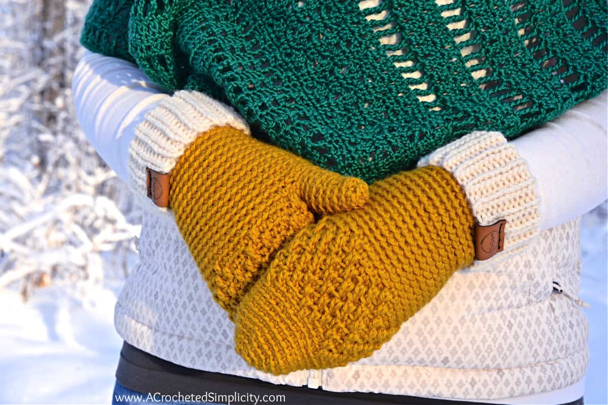 close up of woman modeling mittens crochet pattern in gold and cream
