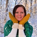 close up of woman holding crochet mittens on her face