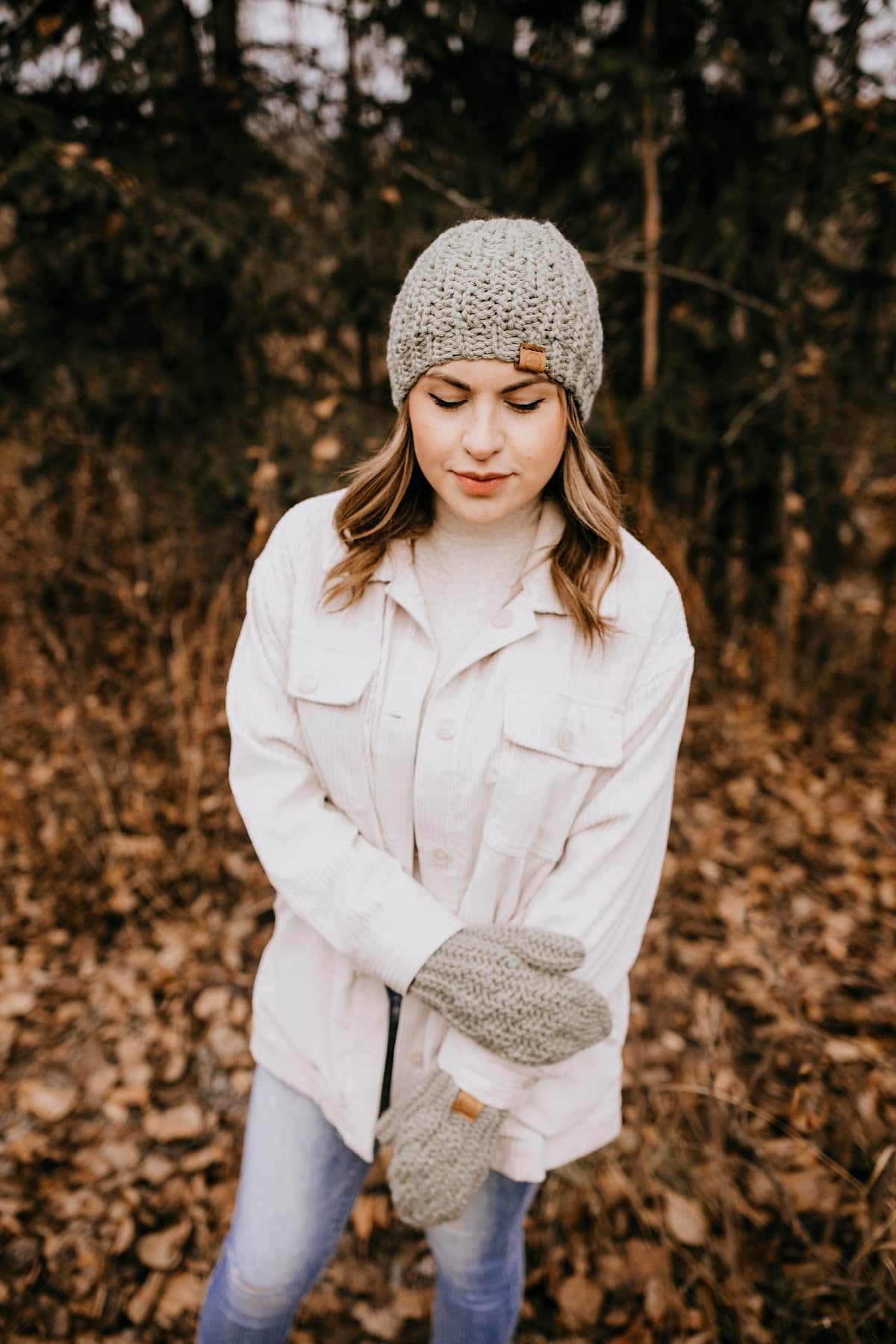 crochet chunky beanie and mitten set modeled by woman outside wearing cream colored jacket