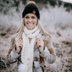 Woman modeling chunky crochet scarf in cream with faux fur poms