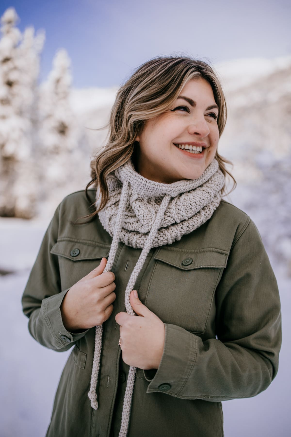 woman smiling modeling crochet drawstring cowl outside in snow