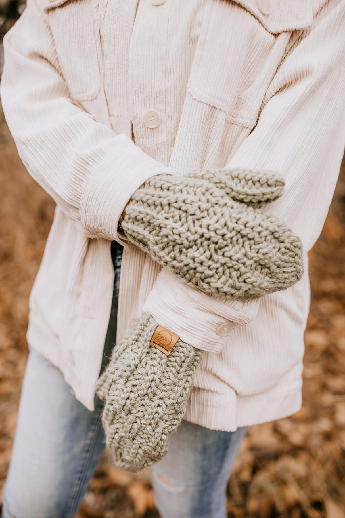 light green crochet mittens modeled by woman wearing a cream jacket