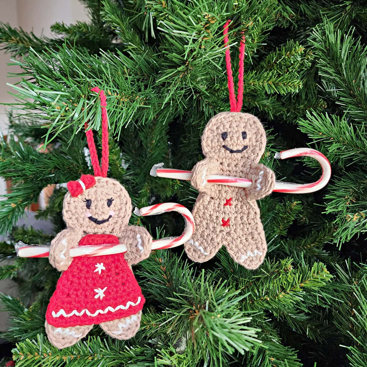two crochet gingerbread man candy cane holder ornaments holding candy canes