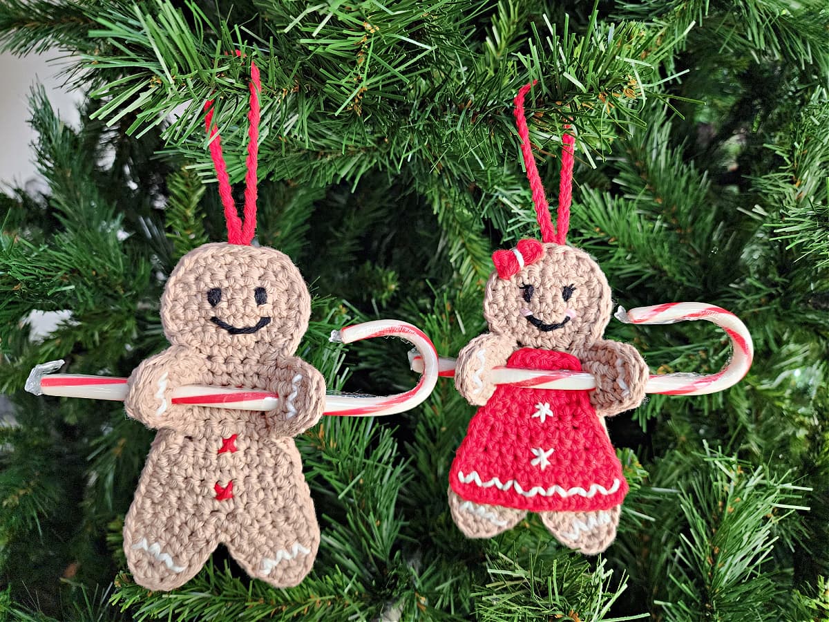 two crochet gingerbread man ornaments hanging on a christmas tree