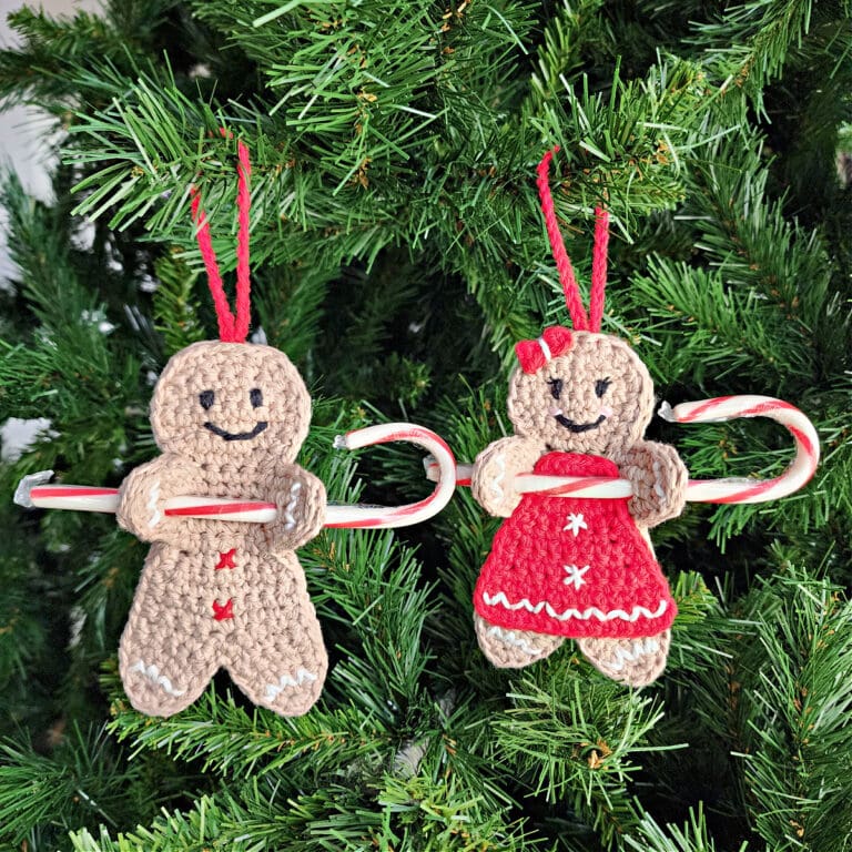 two crochet gingerbread man candy cane holder ornaments hanging on a christmas tree