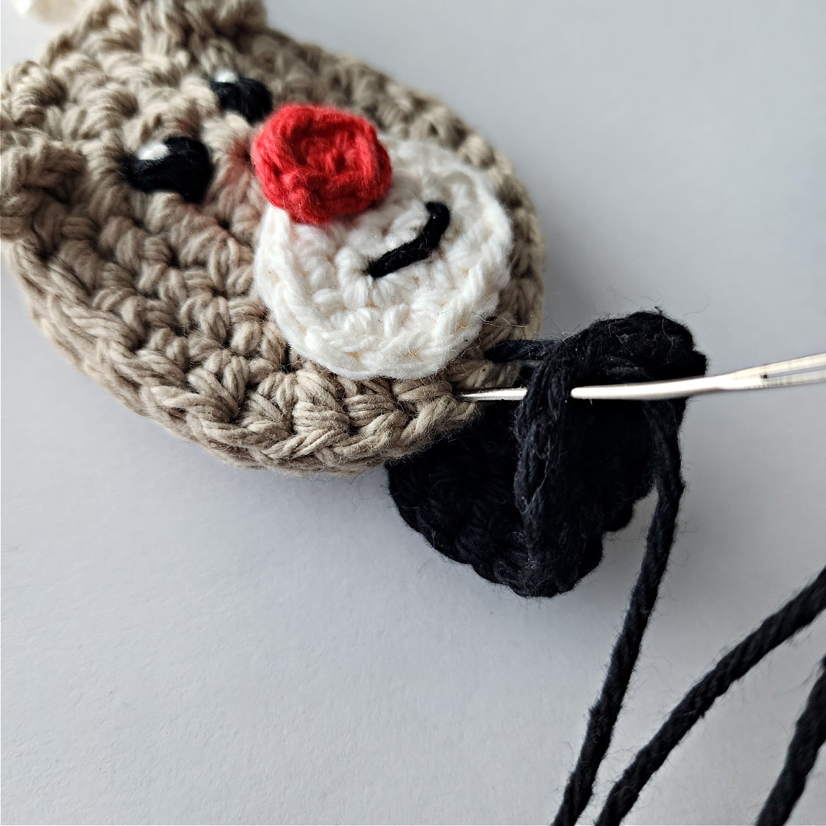 Hoove being sewn onto crochet reindeer candy cane holder ornament.