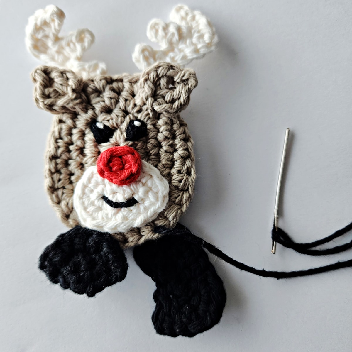 Attaching candy cane holder hooves onto the crochet reindeer candy cane holder ornament.