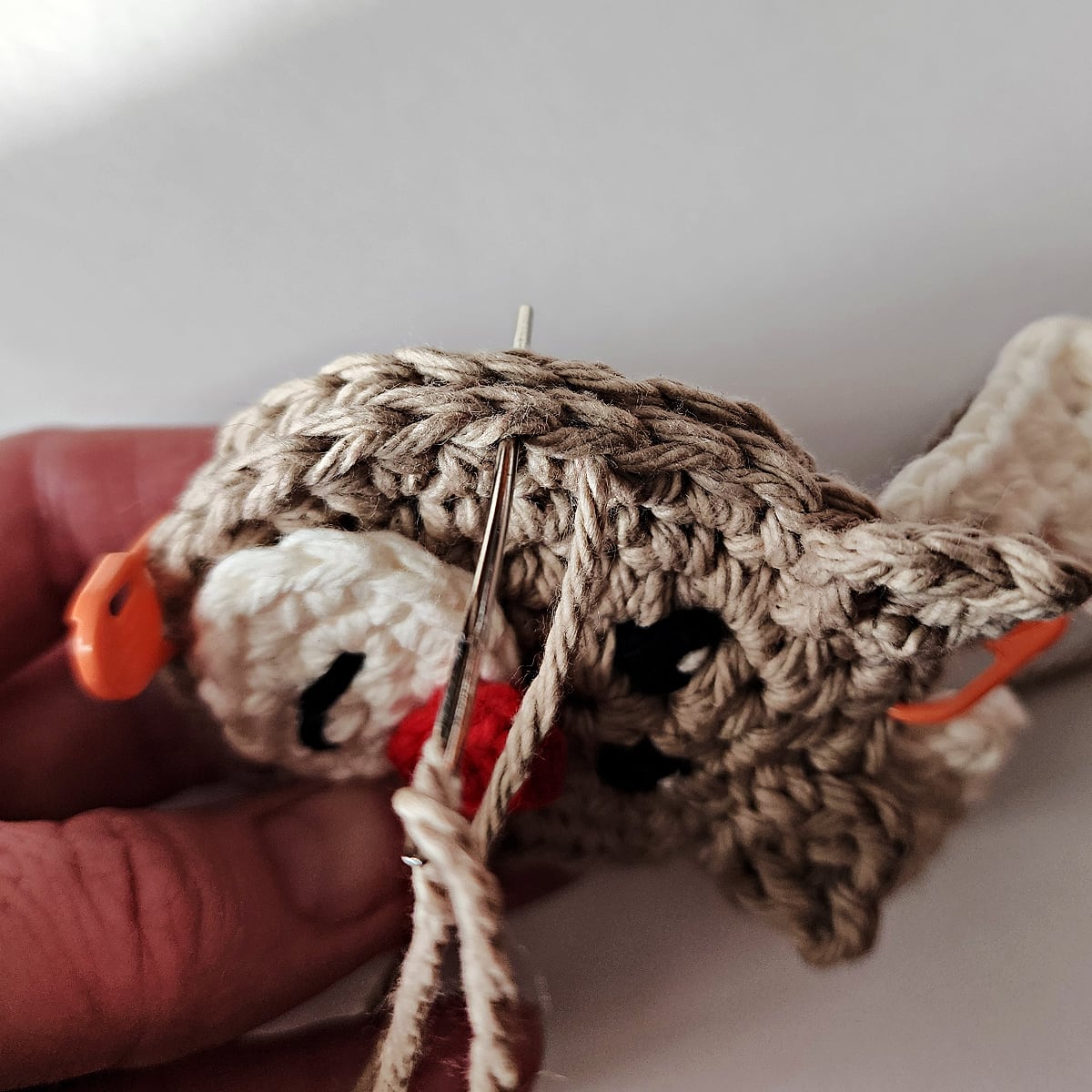 Yarn needle being inserted into the next stitch along the reindeer's head.