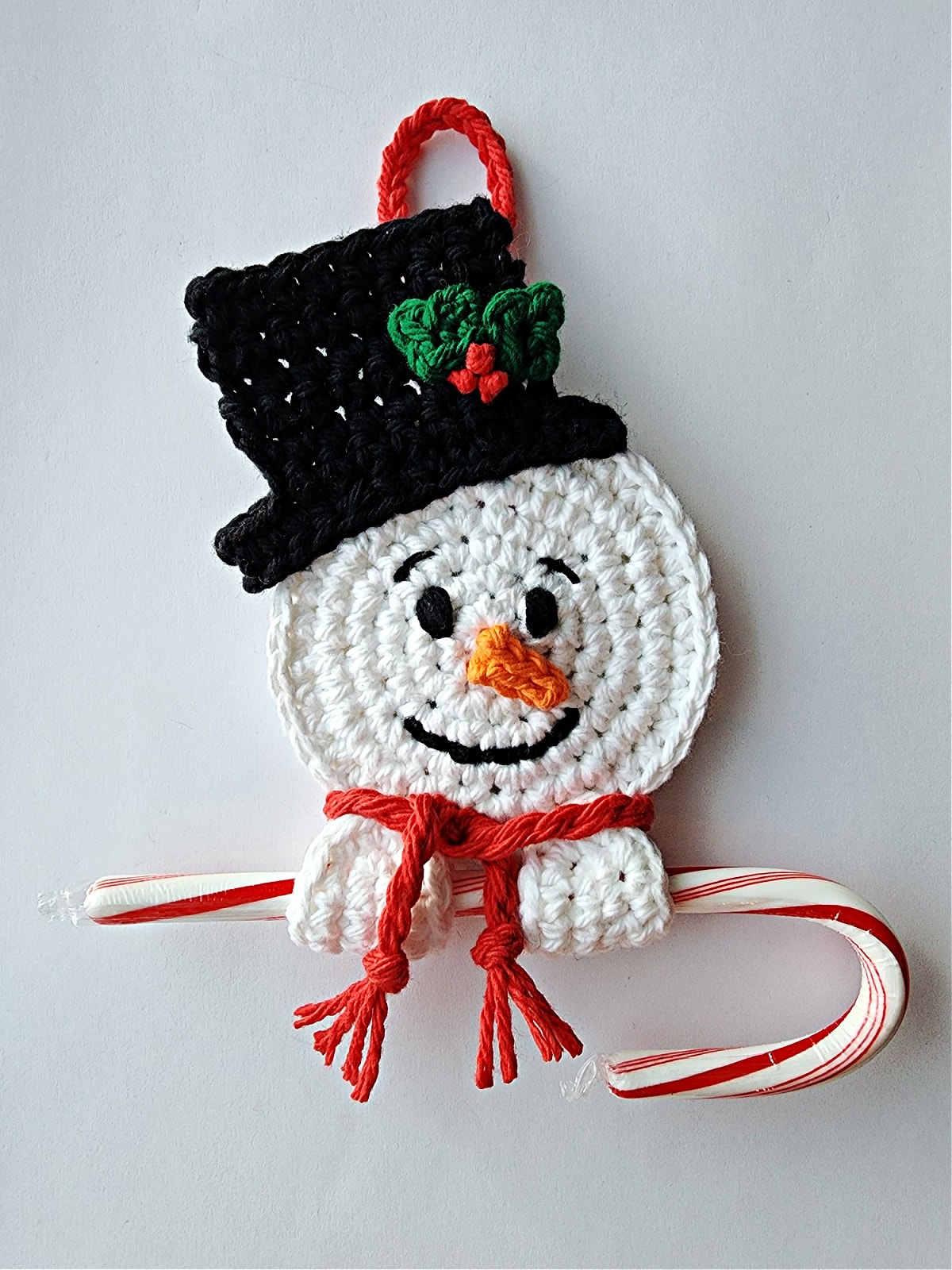 crochet snowman candy cane holder with red and white candy cane