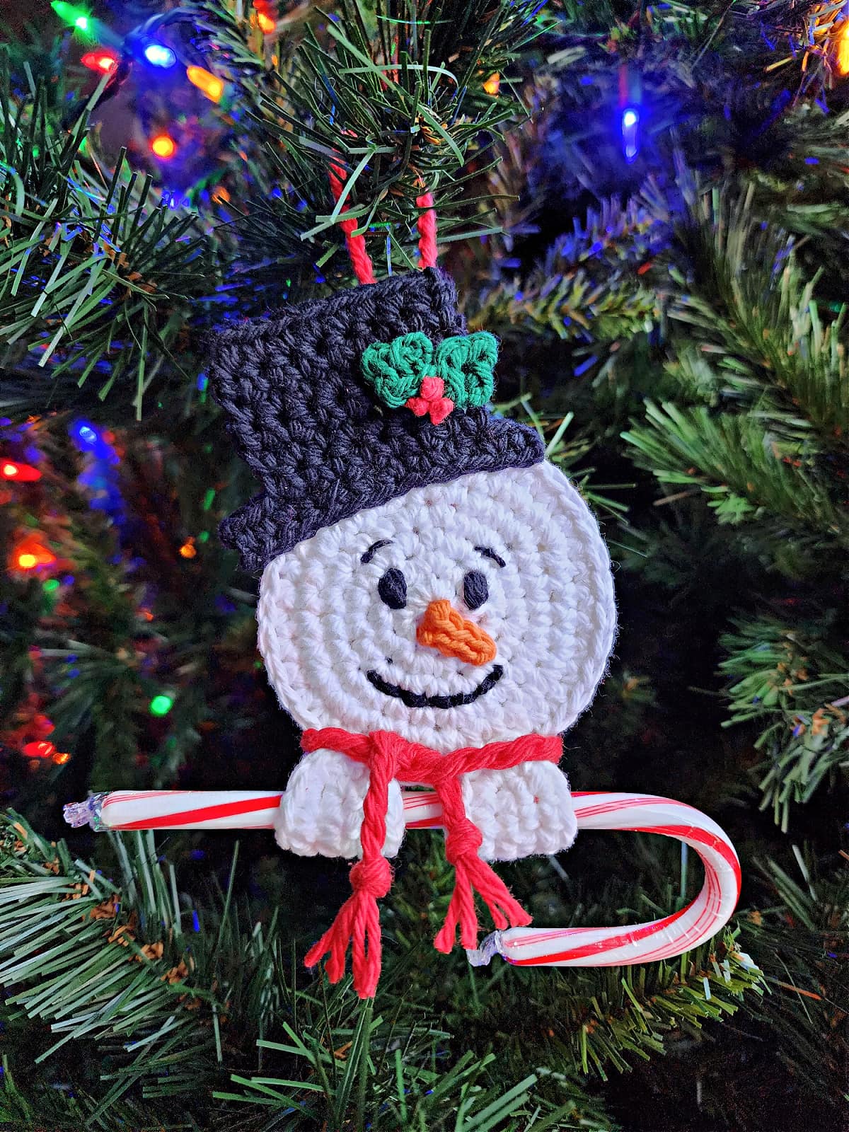 crochet snowman candy cane holder hanging on christmas tree
