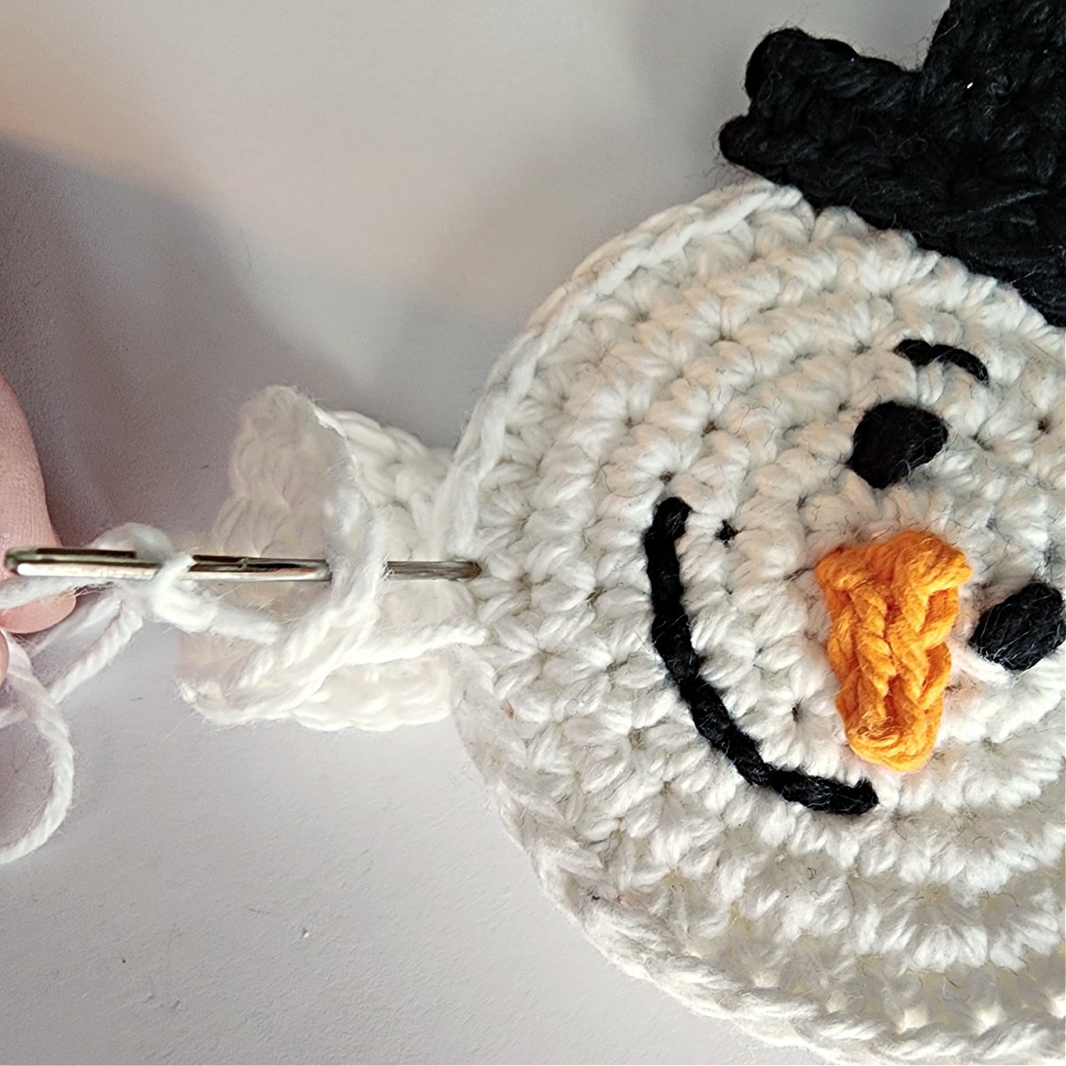 sew crochet hand onto bottom edge of snowman face