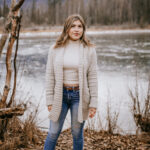 Woman modeling long crochet cardigan with pockets outside in woods.