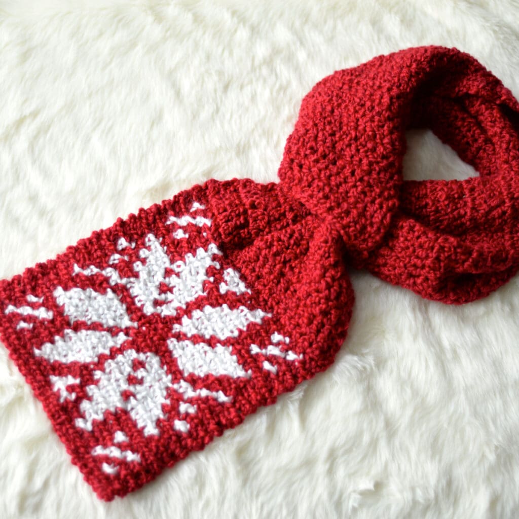 red and white keyhole crochet scarf laying on white fur blanket