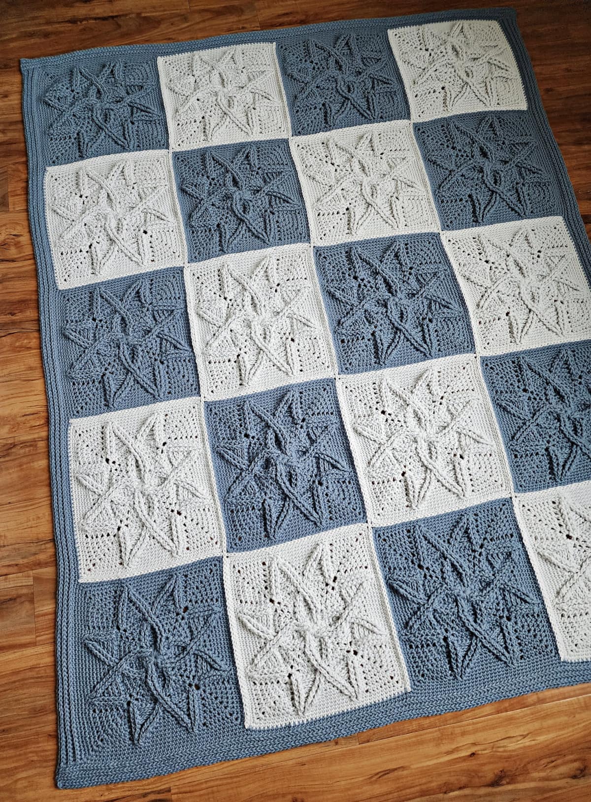 Crochet blanket laying on wood floor.