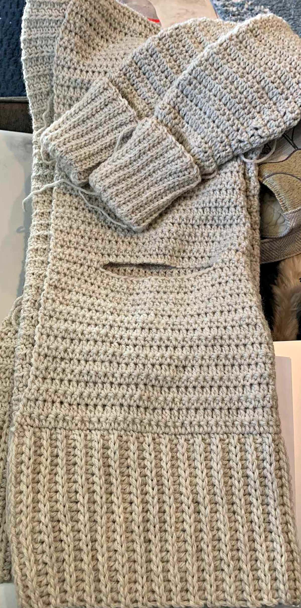 Beige crochet cardigan folded in half to show slit for pocket pouch.