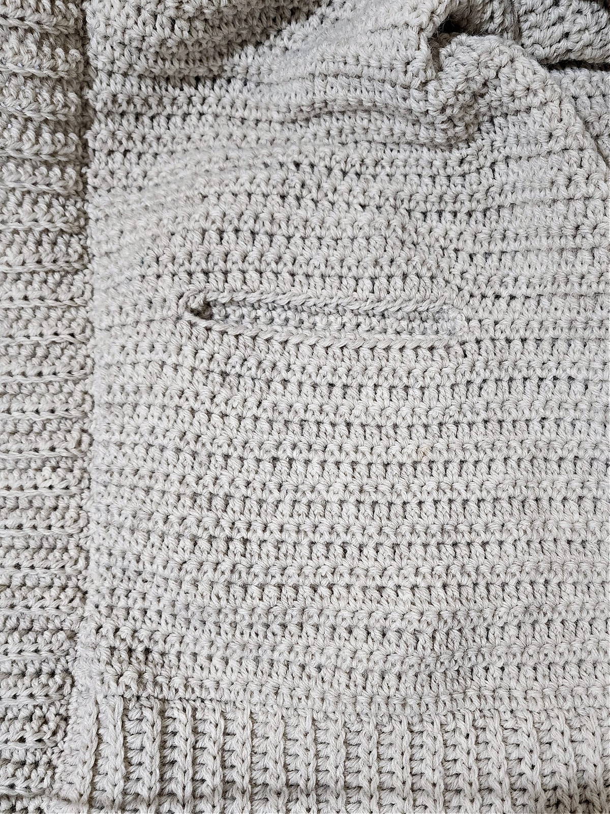 Tutorial photo shows the inset pockets attached to the crochet cardigan.