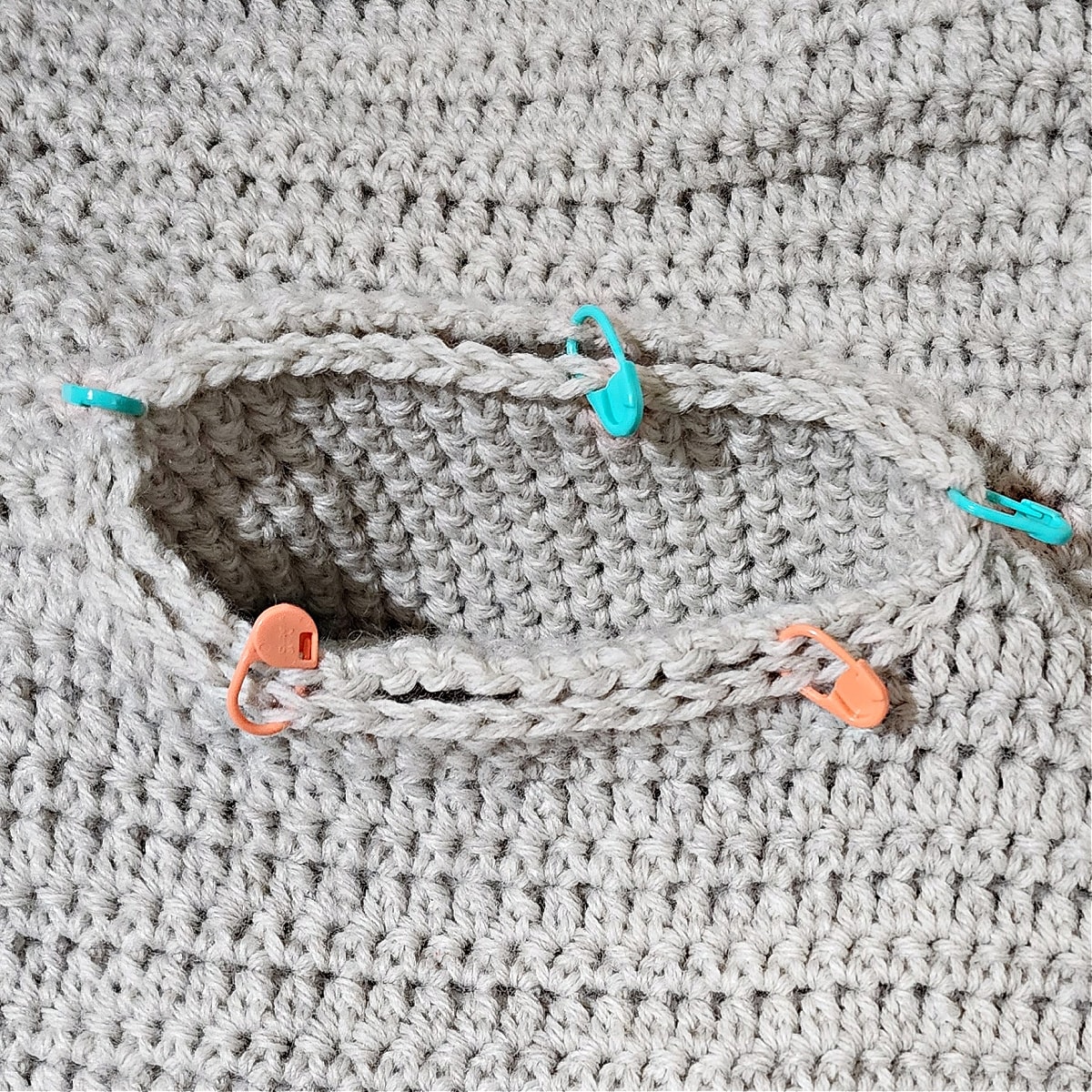 Tutorial photo shows the pocket inserted into the opening on the cardigan and locking stitch markers holding it in place for seaming.