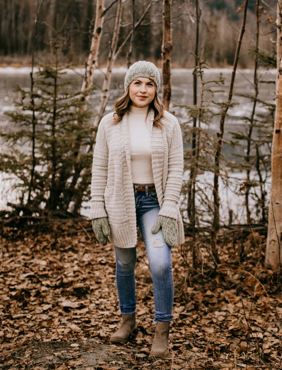 Woman modeling an easy crochet cardigan and a winter hat and mitten set.