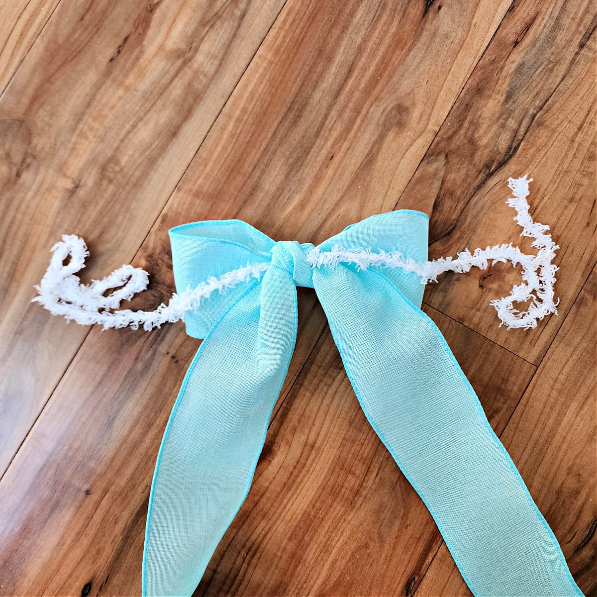Blue bow with yarn attached ready to be attached to crochet bunny wreath.