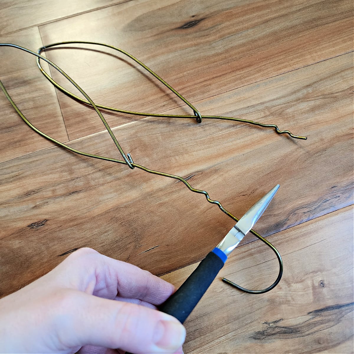 Pliers cutting the hook end of the coat hanger off the bunny ear.