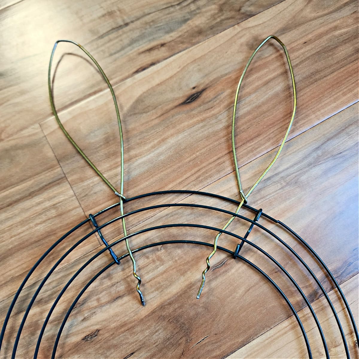 Two metal bunny ears inserted through round wire wreath form.
