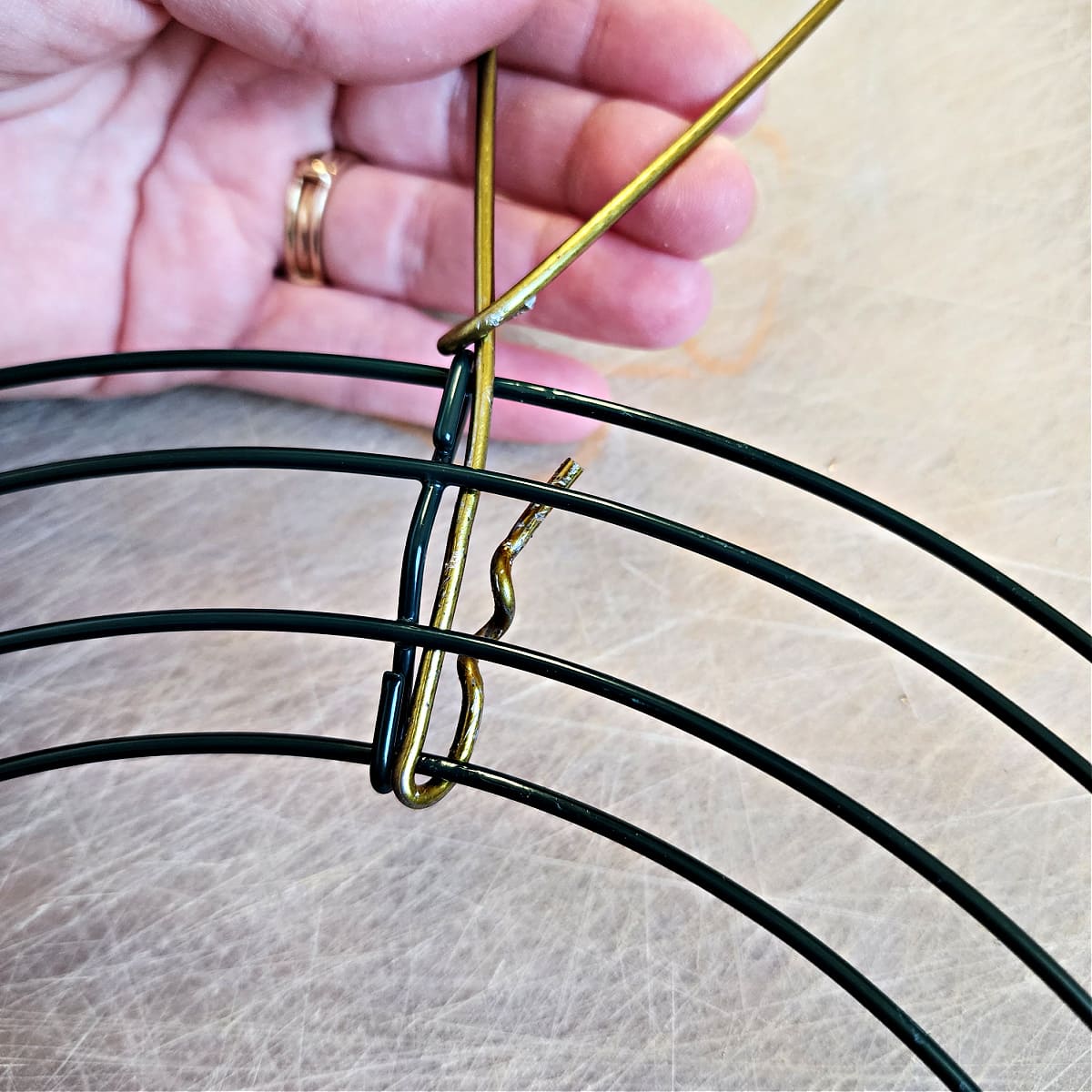 Bend straight end of bunny ear up around wire wreath form to secure it.