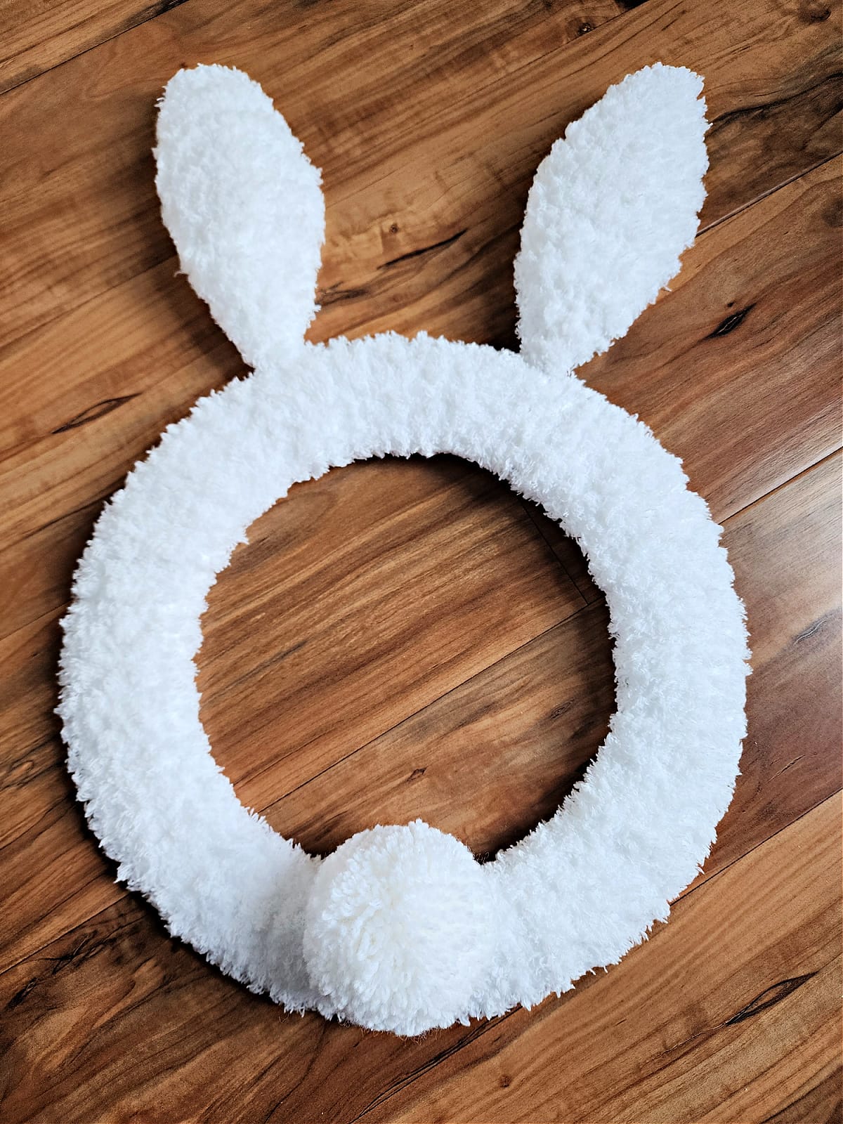Yarn pom tail attached to crochet bunny wreath.