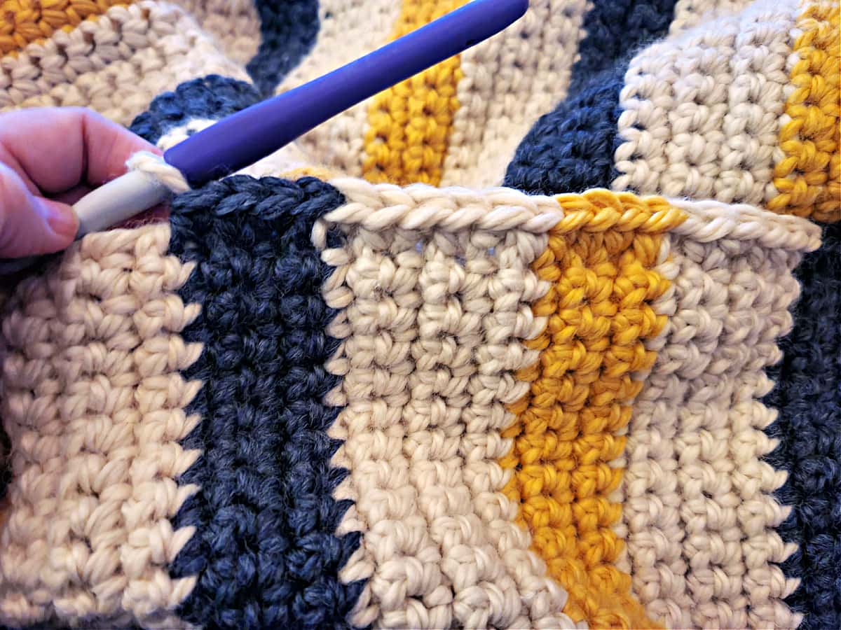 A close-up showing adding a border to a crochet blanket.