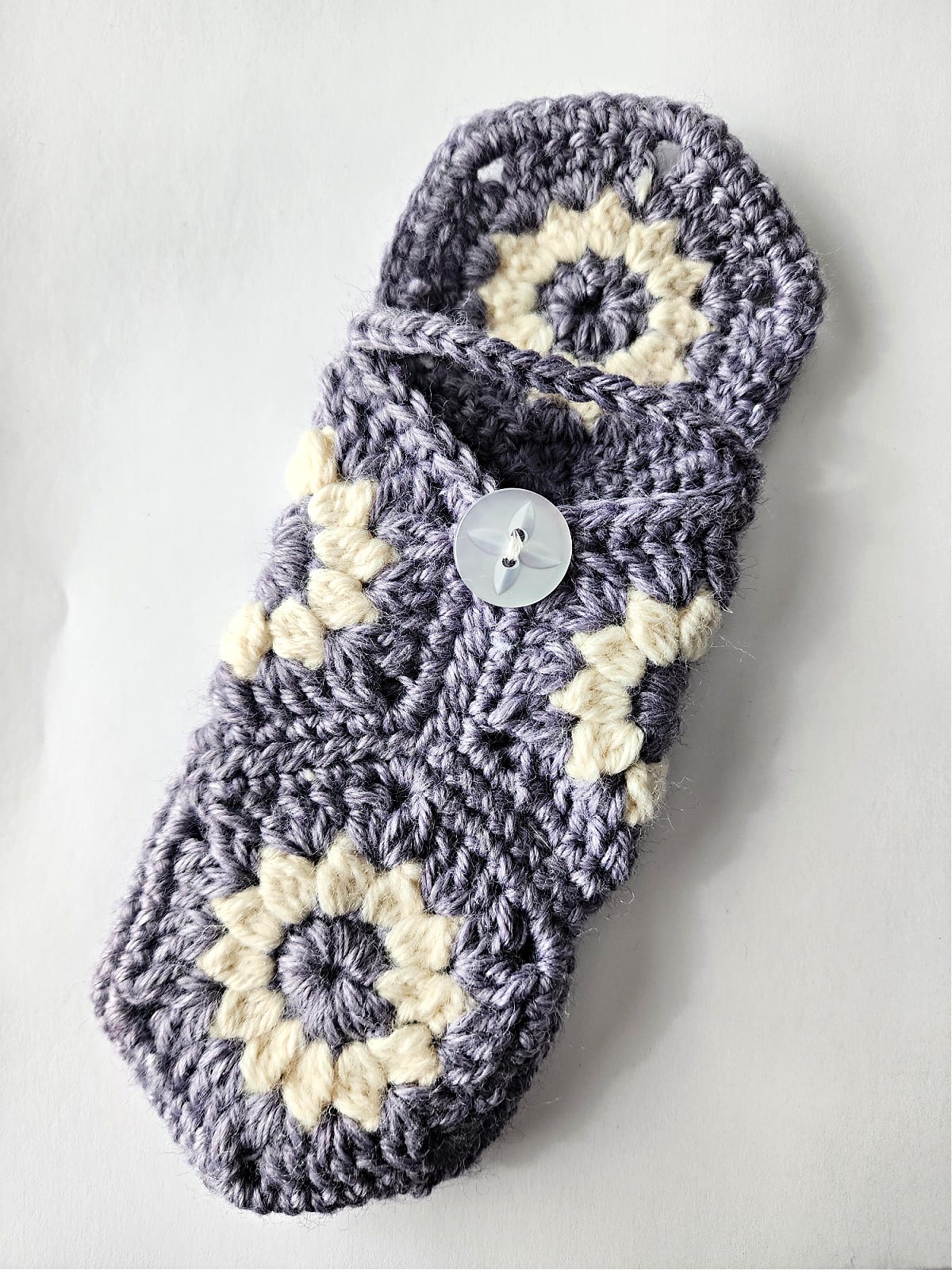 Purple crochet eyeglasses case shows a button sewn on and crohet closer.