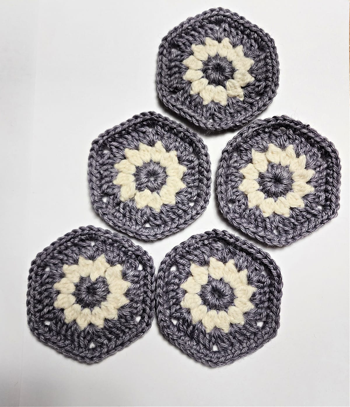 Five purple hexagons with cream crochet flowers.