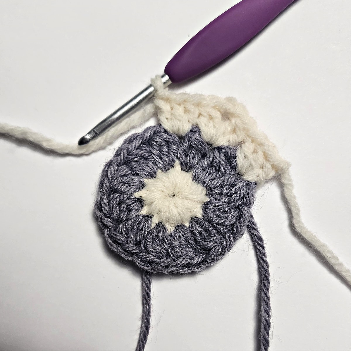 Cream and purple hexagon crochet motif being made.