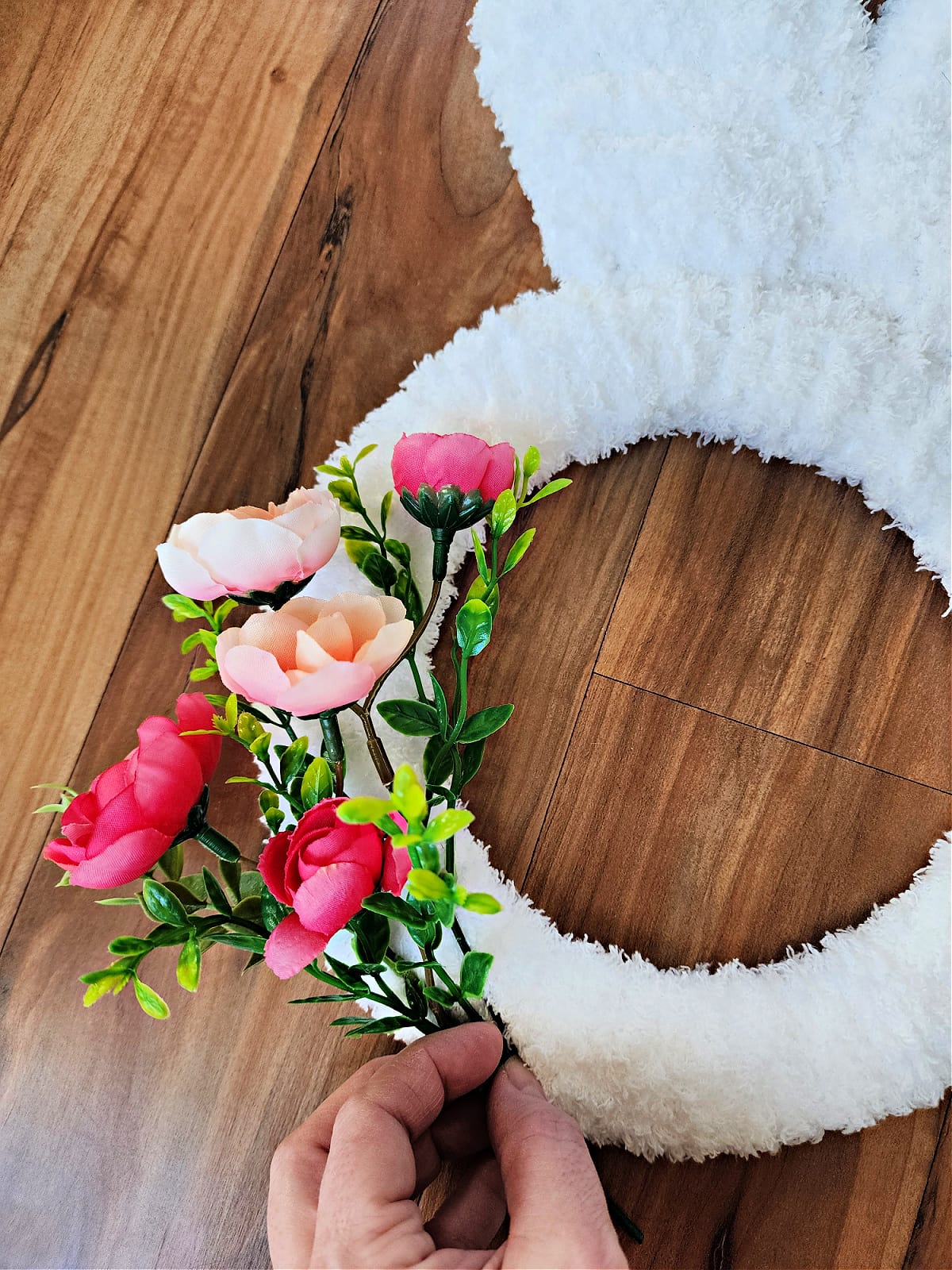 Small pink and peach flowers laying on crochet bunny wreath.