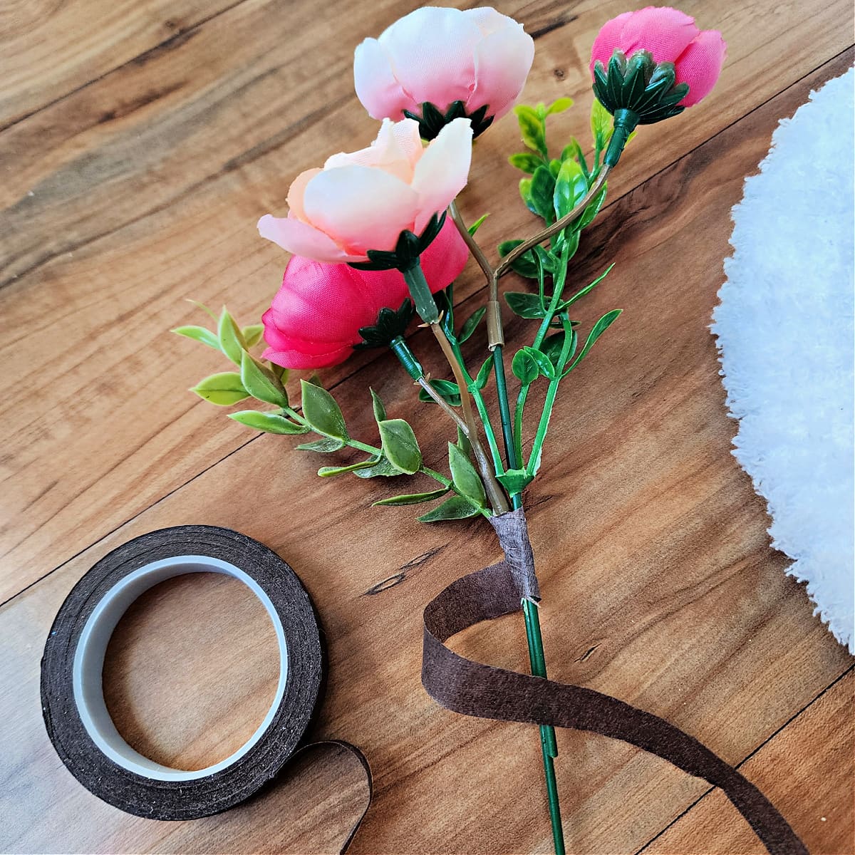 Small bunch of flowers being wrapped with floral tape to hold them together.