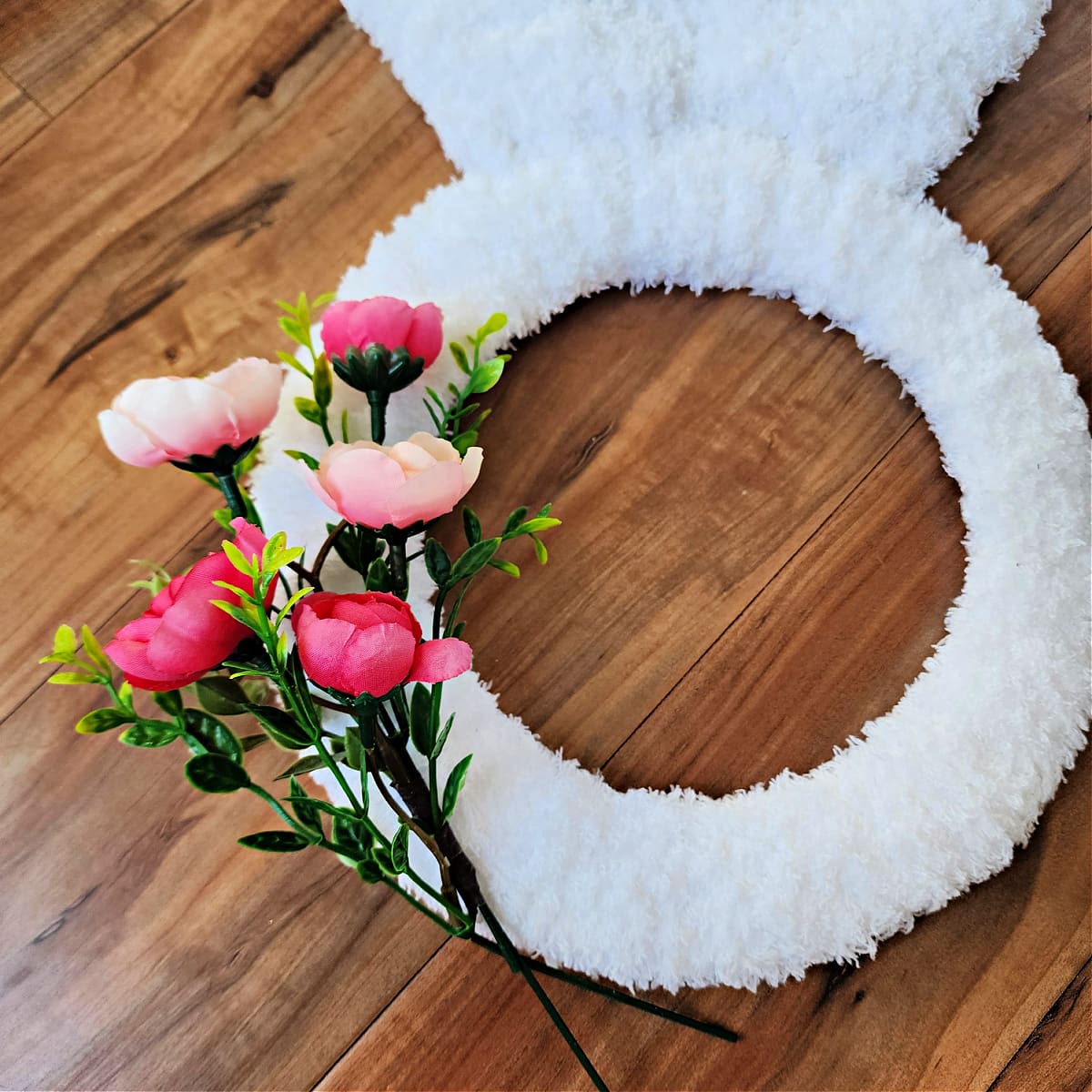 Small sprig of flowers laying on top of crochet bunny wreath.