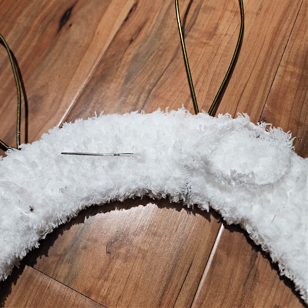 Ends of fuzzy yarn being woven into the back of the crochet bunny wreath.