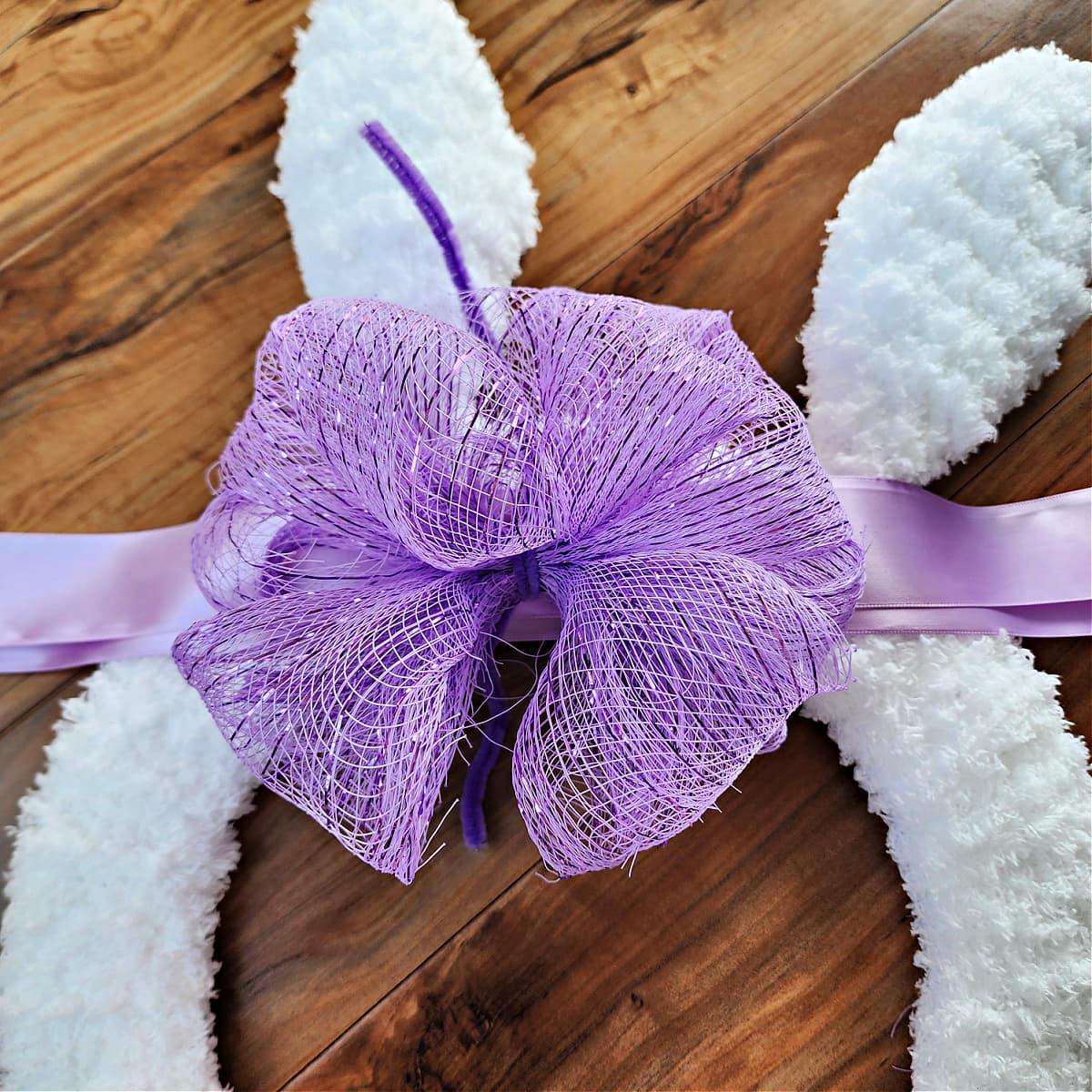 Deco mesh bow laying on top of satin ribbon before being secured.