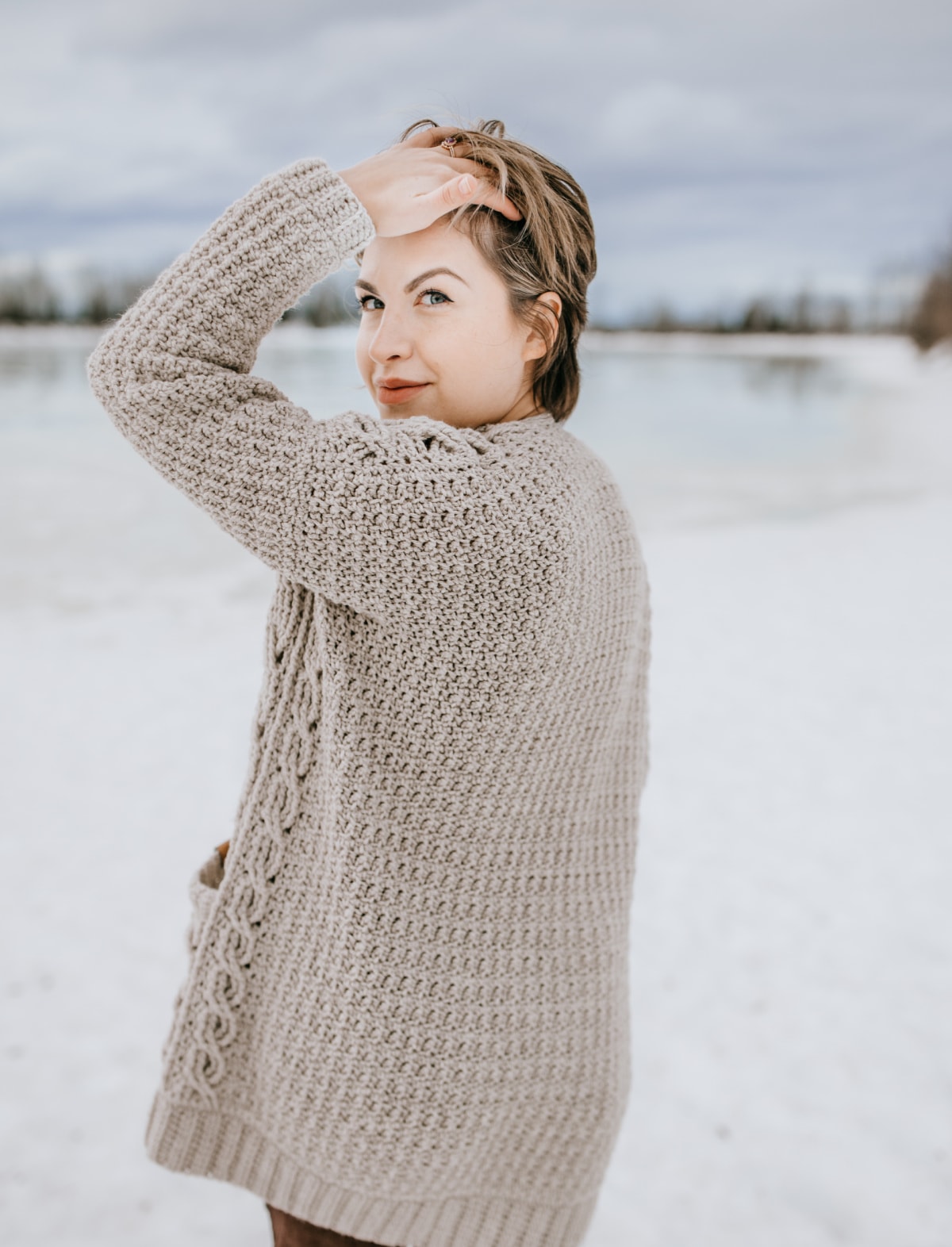 Model showing back side of cabled crochet cardigan.