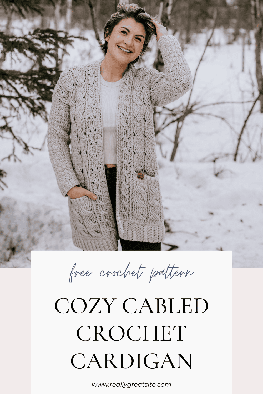 Woman modeling crochet cable cardigan near pine trees.