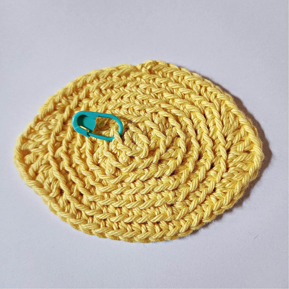 Crochet lemon with a blue stitch marker to mark the center.