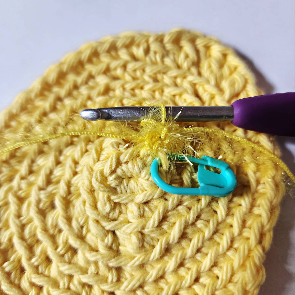 Purple crochet hook with scrubby sparkle yarn to add to the crochet lemon.