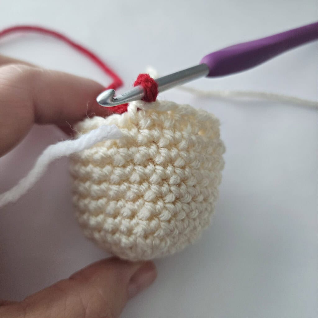 The head of an amigurumi crochet jingle bell ornament.